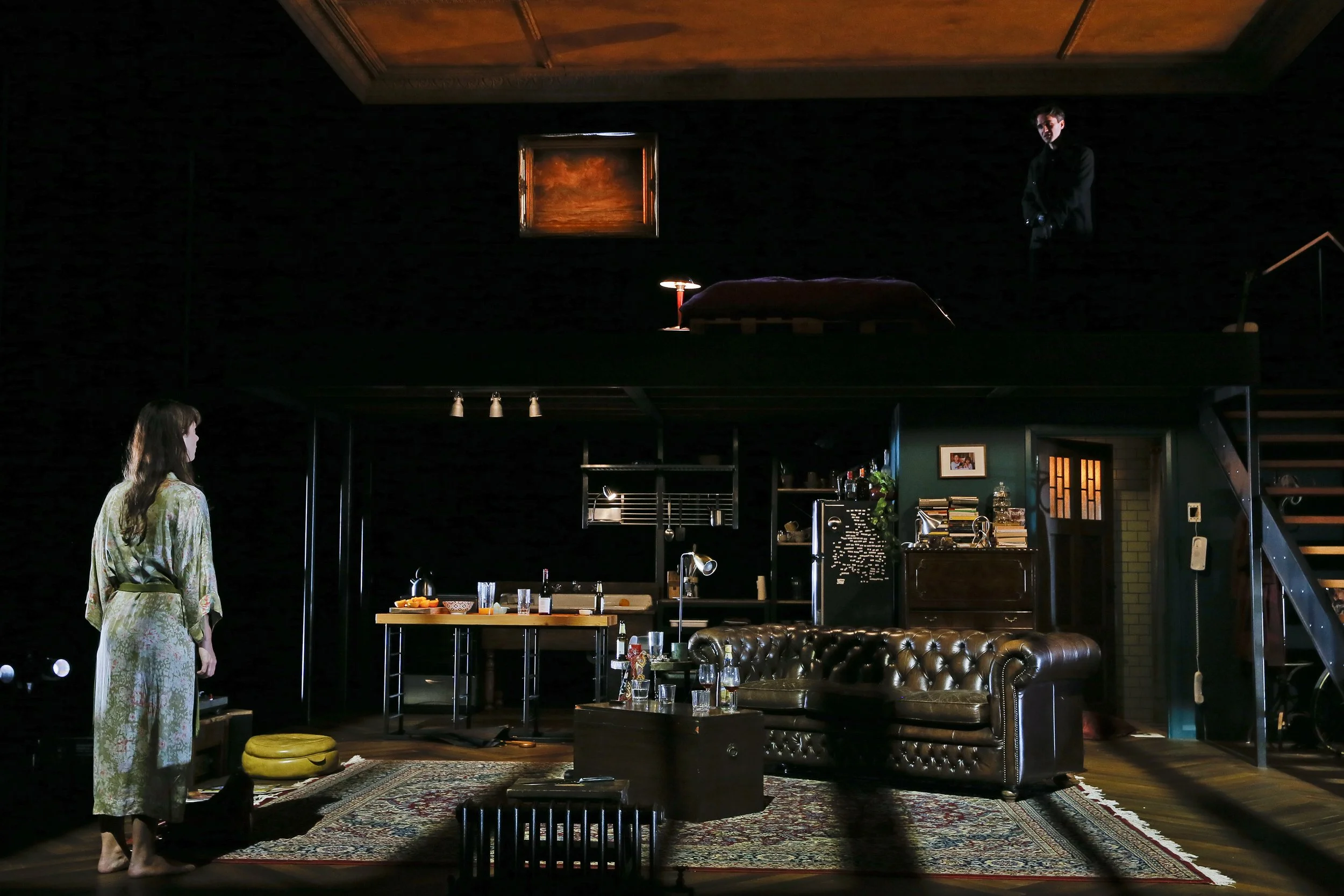 Wide view of the two-level Berlin apartment set with a performer in the lower living room.