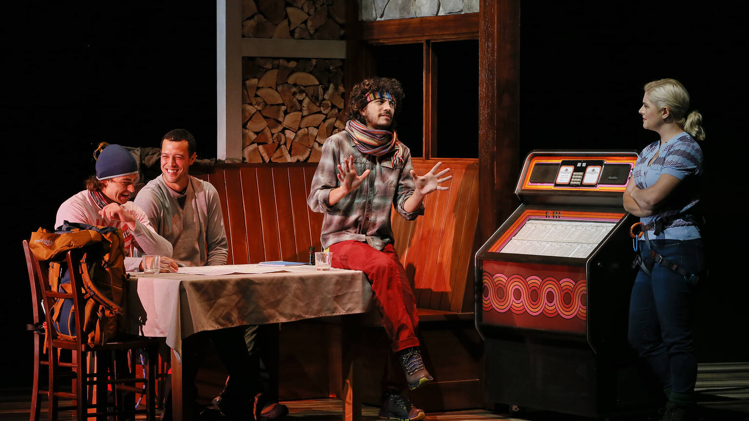 Four people chat around a table in a bar from a scene in Touching the Void