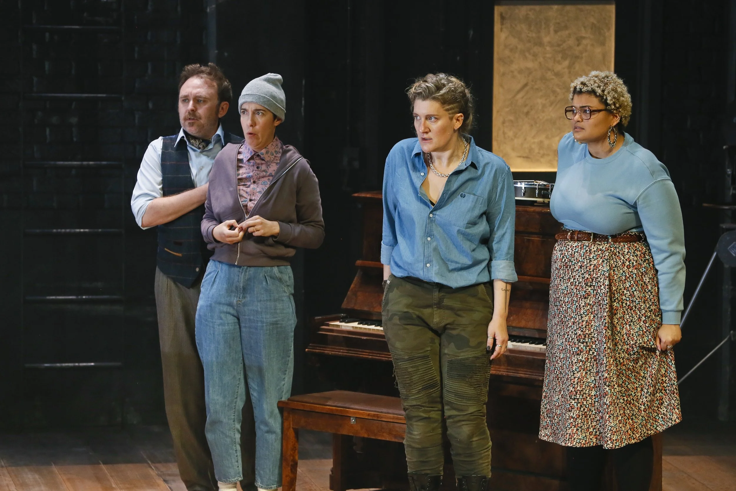 Four Cyrano performers gathered beside an upright piano.